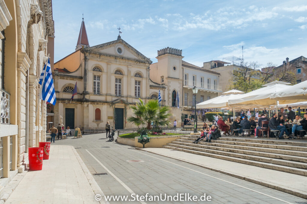 Der Rathausplatz in der Altstadt von Korfu, vor dem Rathausgebäude und neben Kirchen, netten Bars und schönen Cafés